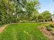 Lush backyard with a well-maintained lawn, mature trees, and a cozy bench for relaxation at 2611 Forest Dr, Charlotte, NC 28211