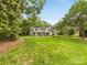 A house with a beautifully landscaped front yard and mature trees under a clear blue sky at 2611 Forest Dr, Charlotte, NC 28211