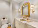 Elegant powder room with a gold framed mirror, decorative sconces, and a marble countertop at 2611 Forest Dr, Charlotte, NC 28211