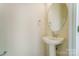 This powder room features a pedestal sink, a round mirror, and neutral colored walls at 2907 W Trade St, Charlotte, NC 28208