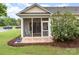Inviting screened porch with a rocking chair and brick flooring overlooking a serene backyard at 31470 Royal Tern Ln, Indian Land, SC 29707