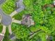An aerial shot reveals a home's roof and backyard, surrounded by vibrant green trees and a paved patio at 5009 Ravens Ct, Matthews, NC 28104