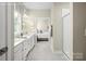 Bright bathroom with dual sinks, white cabinets, tiled floors, and a glass-enclosed shower with a view into bedroom at 523 Lenswood Ct, Denver, NC 28037