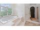 Bright bathroom with a large soaking tub, tiled floor, and a view of the backyard at 5400 Challisford Ln, Charlotte, NC 28226