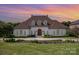 Elegant home with a manicured front lawn and refined landscaping, highlighted by an arched front door at 5400 Challisford Ln, Charlotte, NC 28226
