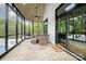 Inviting sunroom with stone floors, ceiling fan, and walls of windows overlooking lush greenery at 5400 Challisford Ln, Charlotte, NC 28226