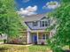 Inviting two-story home featuring stone accents, light grey siding and a bright blue front door at 6541 Hasley Woods Dr, Huntersville, NC 28078