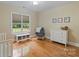 Bright bedroom with hardwood floors, glider chair, white dresser, and natural light from a large window at 7687 Bermuda Hills Ln, Denver, NC 28037