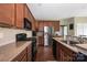 Well-lit kitchen featuring stainless steel appliances, granite countertops, and dark wood cabinets and floors at 9159 Marasol Ln, Concord, NC 28027