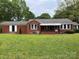 Charming single-story brick home with a well-manicured lawn, awning covered porch, and black trimmed windows at 925 Grace Ave, Lancaster, SC 29720