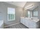 Light-filled bathroom features a double sink vanity with granite countertops and a large mirror at 9321 Bradstreet Commons Way, Charlotte, NC 28215