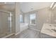 Bright bathroom boasts a glass-enclosed shower, soaking tub, double sinks, and luxury vinyl plank flooring at 9321 Bradstreet Commons Way, Charlotte, NC 28215