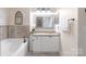 Bright bathroom featuring a soaking tub with tile surround, granite countertop, and decorative mirror at 108 Pier 33 Dr # 414, Mooresville, NC 28117