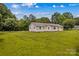 Backyard showcasing the house, green grass and mature trees at 115 Three Oaks Ln, Statesville, NC 28677