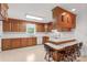 Well-lit kitchen with wooden cabinets, breakfast bar, white appliances and a window over the sink at 115 Three Oaks Ln, Statesville, NC 28677
