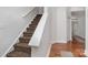 A carpeted staircase with animal print treads and a white banister, transitioning to hardwood flooring at 118 Sunrise Cir, Mooresville, NC 28117