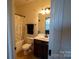 Bright bathroom featuring a vanity with dark wood cabinets, toilet, and shower with patterned curtain at 126 W Warfield Dr, Mooresville, NC 28115