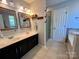 Bathroom featuring double sink vanity, tile floors, glass shower, and soaking tub at 13241 Woodland Farm Dr, Charlotte, NC 28215