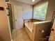 Bathtub and shower area features decorative tile work, storage area, and bright light at 13241 Woodland Farm Dr, Charlotte, NC 28215
