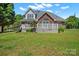 Expansive backyard featuring a brick home with a white deck, lush green lawn, and mature trees at 14340 Kendalton Meadow Dr, Mint Hill, NC 28227