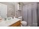 Bright bathroom with a wood cabinet sink, toilet, shower curtain, and decorative wall art at 14340 Kendalton Meadow Dr, Mint Hill, NC 28227