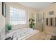Bright bathroom featuring a soaking tub, a shower and natural light from a glass block window at 14340 Kendalton Meadow Dr, Mint Hill, NC 28227