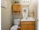 Cozy bathroom featuring wood cabinets, sink, toilet, mirror, and storage; stairs visible in the background at 14340 Kendalton Meadow Dr, Mint Hill, NC 28227