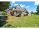 Two-story brick home with a well-maintained lawn, white deck, and mature trees at 14340 Kendalton Meadow Dr, Mint Hill, NC 28227