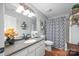 Well-lit bathroom with white cabinets, granite counters, tile floors, decorative shelving, and patterned shower curtain at 184 Quiet Cove Rd, Mooresville, NC 28117
