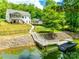 Exterior view of a white two-story home with a screened-in porch, outdoor structure, and dock on the lake at 184 Quiet Cove Rd, Mooresville, NC 28117