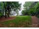 Expansive backyard with lush lawn, mature trees, and a view of the charming home at 19523 Sunnypoint Ct, Cornelius, NC 28031
