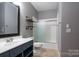 Bathroom with a blue vanity, decorative shelves, and a shower-tub combo at 19523 Sunnypoint Ct, Cornelius, NC 28031