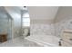 Bright bathroom featuring a soaking tub, toilet, marble floors and unique tiling at 19523 Sunnypoint Ct, Cornelius, NC 28031