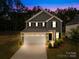 Two-story home featuring a two-car garage, landscaped yard, and classic architectural details at dusk at 2012 Slippery Rock Ln, Monroe, NC 28112