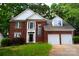 Traditional two-story red brick home with a two-car garage and lush green trees around the house at 2608 Yarrow Rd, Charlotte, NC 28213
