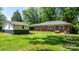 View of the backyard, which features green grass and a brick home with blue shutters and a matching storage shed at 3418 Sulphur Springs Ne Rd, Hickory, NC 28601