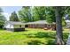 View of the backyard with green grass, a brick home with blue shutters, and a matching storage shed, with a tree in the foreground at 3418 Sulphur Springs Ne Rd, Hickory, NC 28601