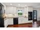 Bright kitchen with white cabinets, modern appliances, a farmhouse sink, and hardwood floors at 3918 Rea Rd, Charlotte, NC 28226