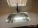 Close-up of a stainless steel kitchen sink with a modern faucet, set into a white countertop under a window at 4025 Grommet Ct, Matthews, NC 28105