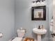 Charming half bathroom featuring a pedestal sink, framed mirror, and light blue walls at 46827 Tall Whit Rd, New London, NC 28127