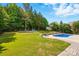 Beautiful backyard featuring an in-ground pool, lush green lawn, and a seating area with mature trees at 5105 Paisano Ln, Waxhaw, NC 28173