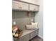 A mudroom area with cabinets, bench, storage, hooks, pillows, basket, and a neutral color scheme at 5817 Tuckaseegee Rd, Charlotte, NC 28208