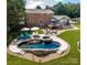 Aerial view of a brick two-story home showcasing a stunning pool with a hot tub, stone patio, and outdoor seating area at 8005 Island View Ct, Denver, NC 28037