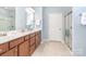 Bright main bathroom with double sink vanity, walk-in shower, and a tile floor at 8033 Pawleys Ct, Fort Mill, SC 29707