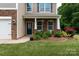 Inviting front porch with stone accents and a beautifully landscaped front yard with colorful roses at 109 Meadow Stream Dr, Mount Holly, NC 28120