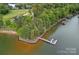 Scenic aerial view of a waterfront property with a private dock, surrounded by lush trees and tranquil water at 112 Nautilus Ct, Troutman, NC 28166