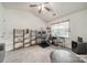 Cozy spare bedroom features a ceiling fan, window, shelves, desk, and neutral colored carpet at 11515 Retriever Way, Charlotte, NC 28269