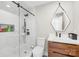 Modern bathroom with a walk-in shower with glass door, sleek vanity, and stylish geometric mirror at 12613 Oak Grove Rd, Stanfield, NC 28163