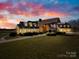 Home at twilight showcases a grand entrance and attached garage with dormer windows at 12613 Oak Grove Rd, Stanfield, NC 28163