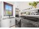 Modern laundry room with sleek washer and dryer, ample storage, and natural light from a window at 12613 Oak Grove Rd, Stanfield, NC 28163